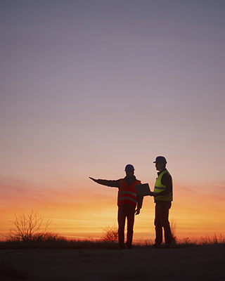 Construction workers surveying at sunset